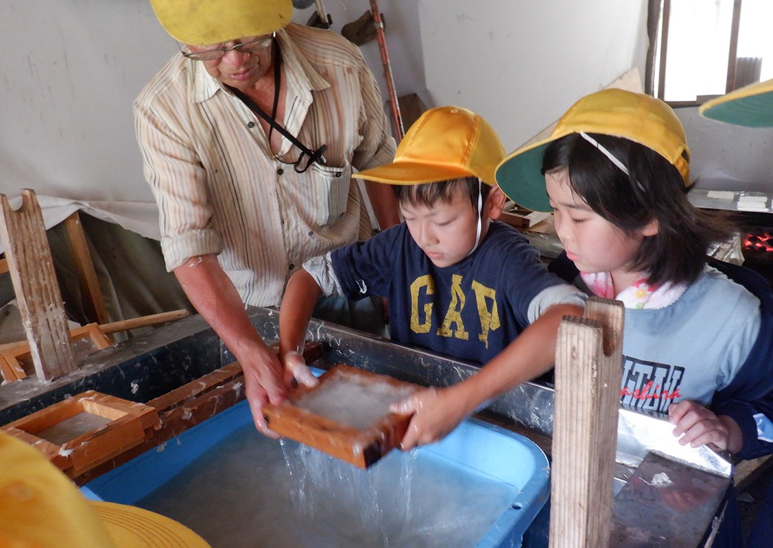 和紙づくり集落を訪れ、紙すきを教わる子どもたち