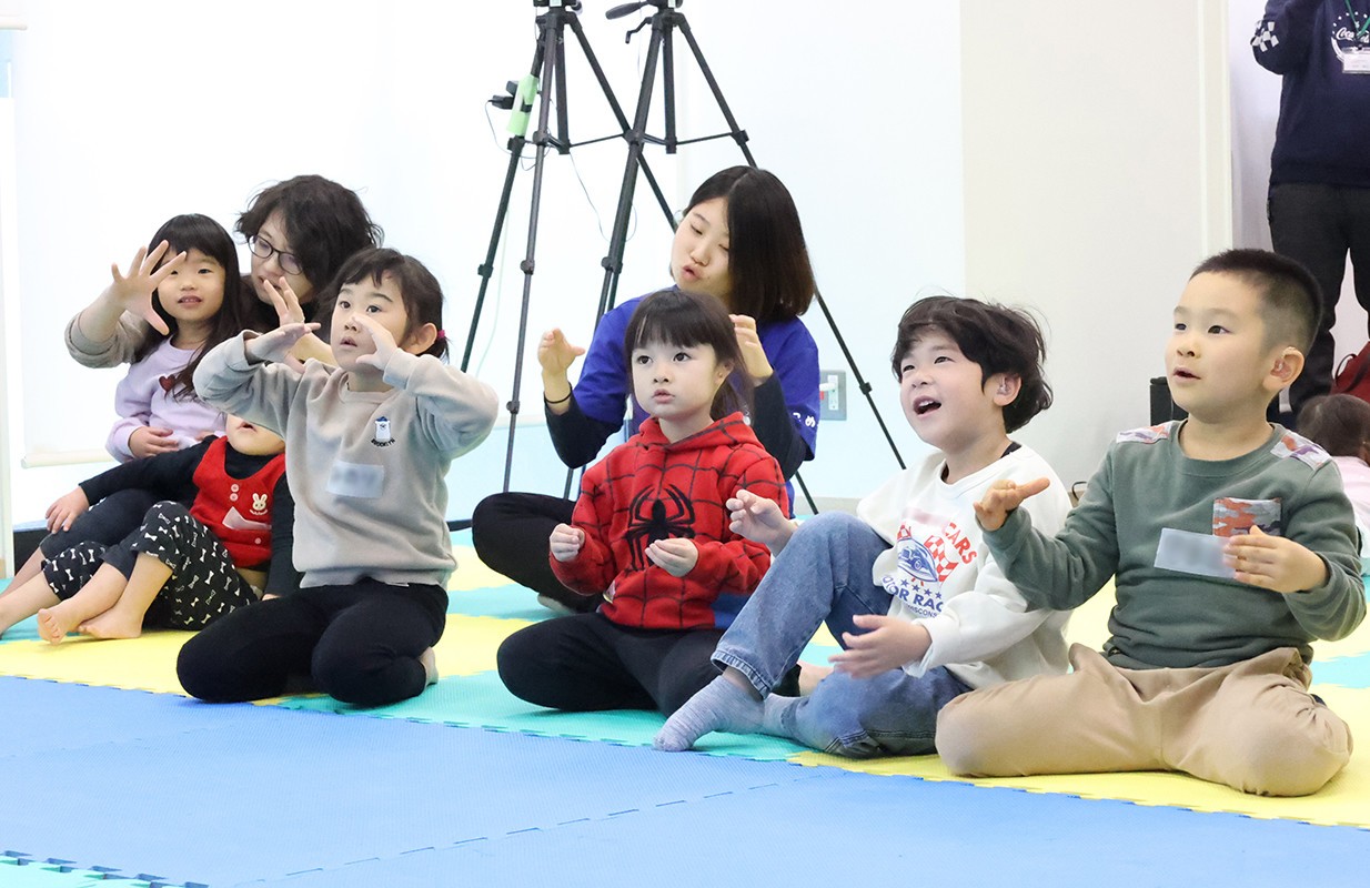 スタッフの手話の動きをまねる子どもたち