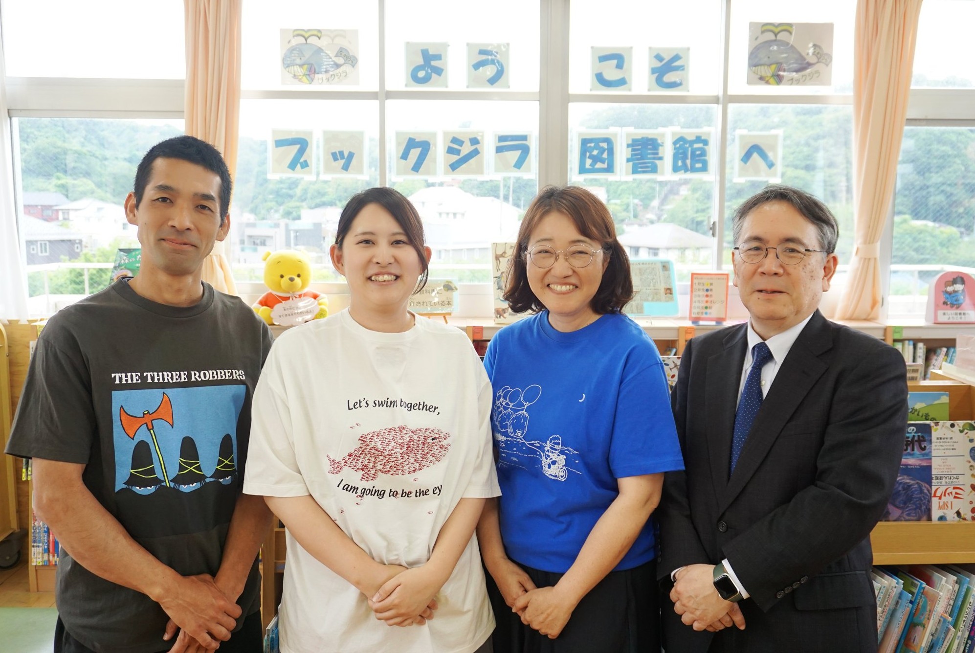 ブックジラ図書館で写る坂本幸太郎司書教諭、田中響子教諭、矢田部磨貴子学校司書、中馬淳常務理事