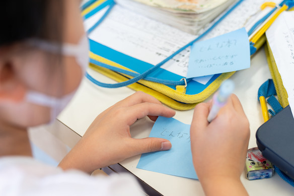 青いふせんに本の印象を書き込む子どもの手元