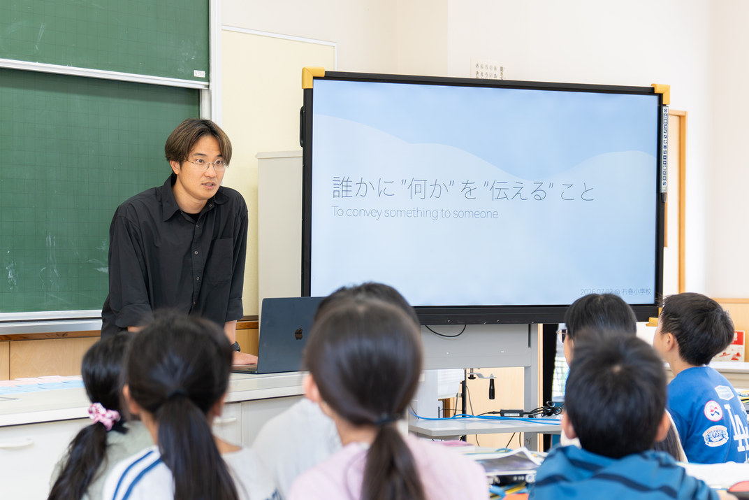 教室の前でスクリーンを使って子どもたちに語りかける講師の山内佑輔さん